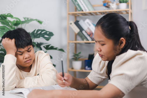 Female tutor helping little elementary school boy with homework during individual lesson at home, Sister helping boy writing lesson and learning to write, Education home school concept.