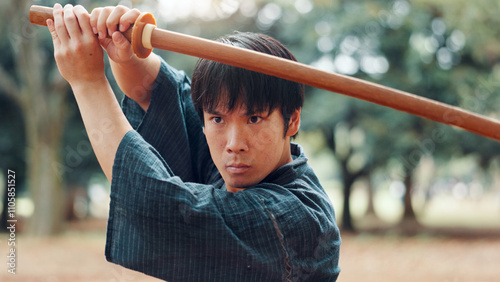 Wooden sword, Japanese man and outdoor for martial arts in training, exercise and sport for culture. Person, weapon and heritage for challenge, combat or practice as self defense technique in bojutsu photo