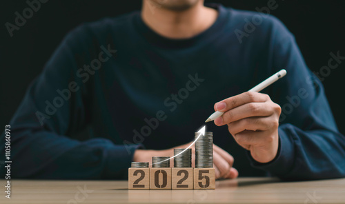 a person uses a pen to point stacked coins on wooden blocks upcoming new year 2025, financial growth, investment planning, new business beginnings, financial growth, and strategic planning and goals