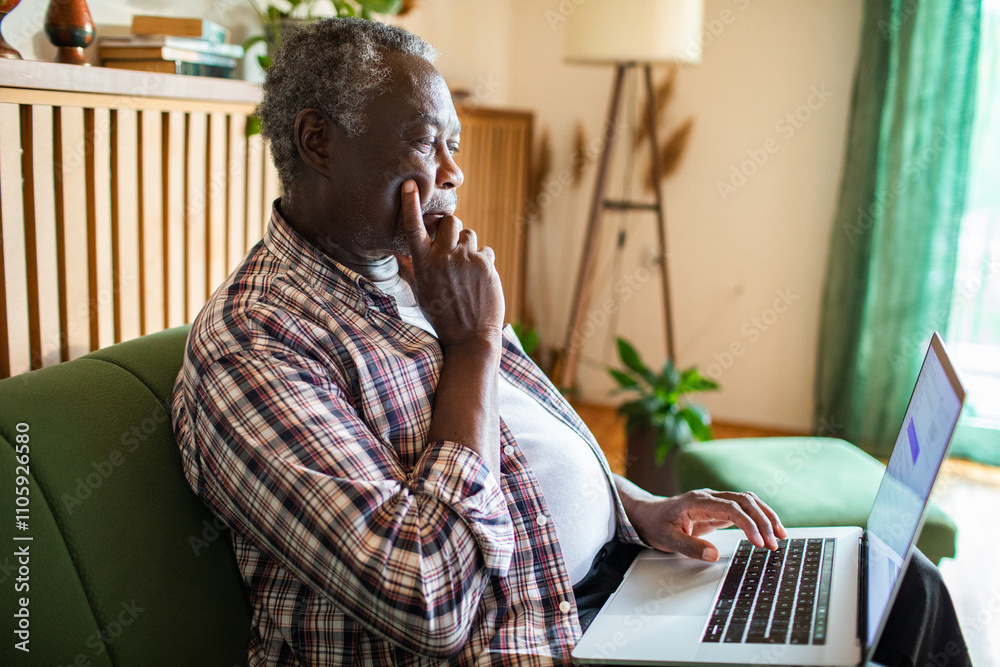 Senior man working on laptop at home in cozy living room Senior man working on laptop at home in cozy living room