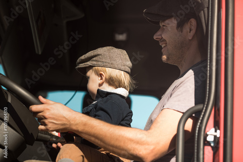 A Cute little boy driving is fathers truck with Dad