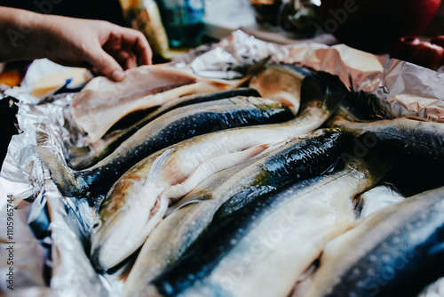 Salting raw fish before cooking in the kitchen. Preparing trout for baking in a roasting pan. Cooking in the home kitchen, fish for holidays, fish dishes. photo