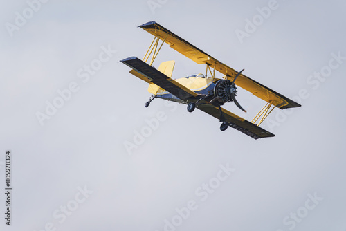 A yellow biplane in the sky. Close up view.