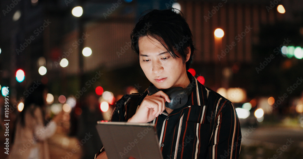 Creative, serious and man with tablet, night and video editor with ideas, headphones and project. Content creation, contemplating and Asian person with tech, post production and process in Japan