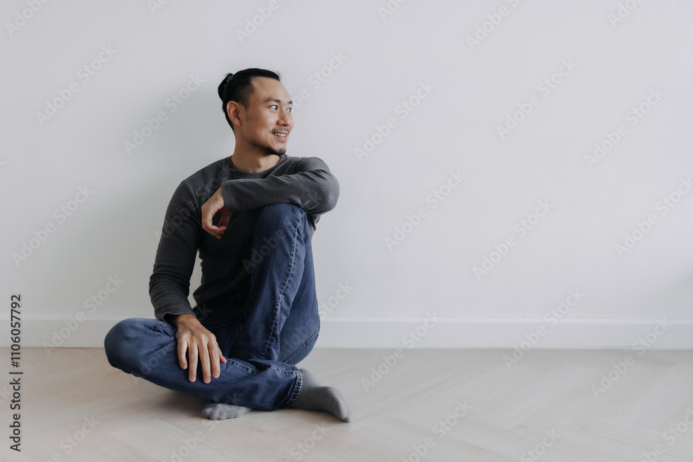 Happy creative freelance Asian man sitting on the floor smile and looking out. Happy creative freelance Asian man sitting on the floor smile and looking out.