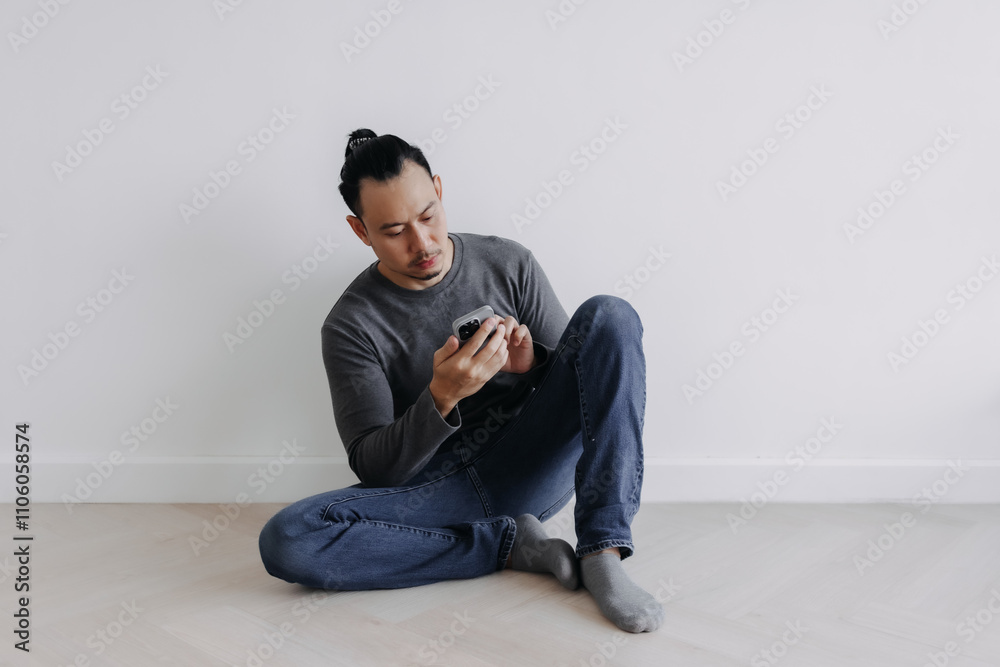 Creative freelance Asian man sitting on the floor looking at the phone. Creative freelance Asian man sitting on the floor looking at the phone.