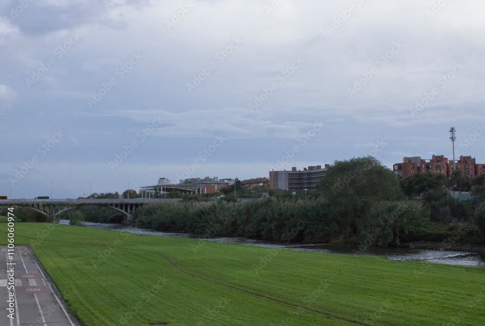 view of a large green field by the river; cityscape view of a large green field by the river; cityscape
