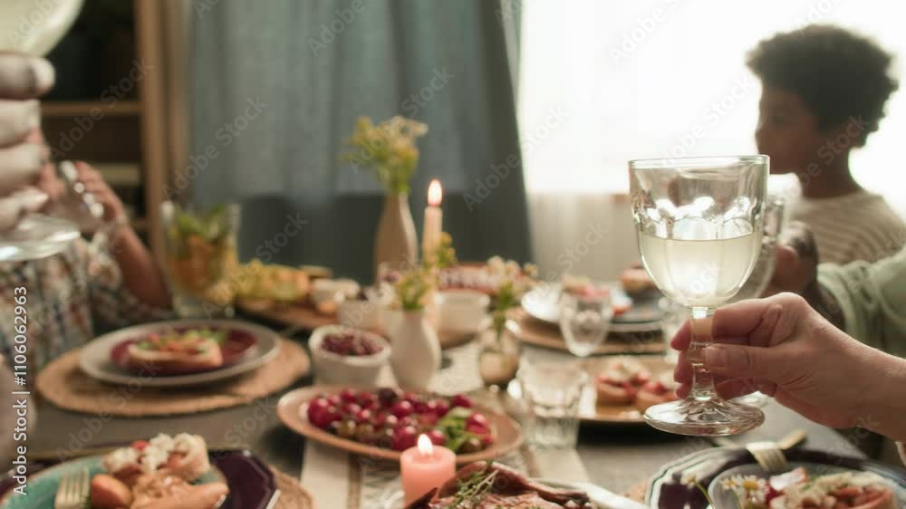 Close-up view of senior man and three unknown relatives clinking glasses in toast while celebrating at festive table, two kids eating in background Close-up view of senior man and three unknown relatives clinking glasses in toast while celebrating at festive table, two kids eating in background