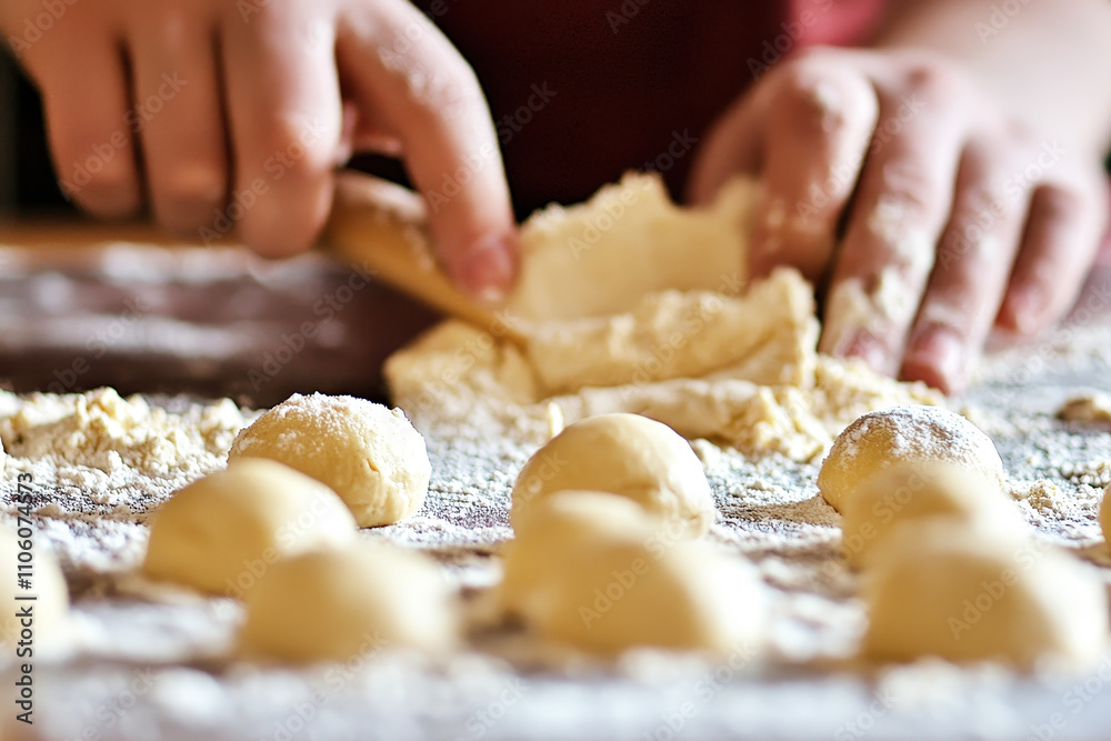 A person hands-on kneading dough and shaping it into small balls, surrounded by flour on the kitchen counter A person hands-on kneading dough and shaping it into small balls, surrounded by flour on the kitchen counter