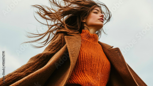 Female mid-section in brown coat and orange sweater twirling in the breeze outdoors photo