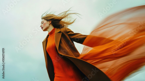 Mid-twirl display of a woman in a brown coat and orange sweater against a soft backdrop photo