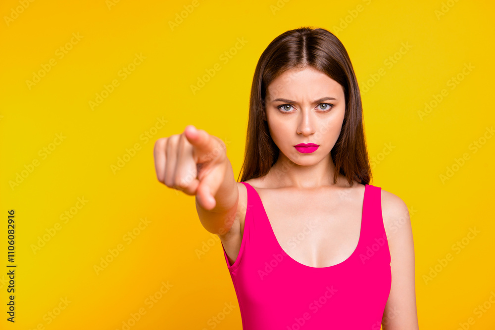 People emotions concept. Close up portrait of upset girl look on camera and points finger forward isolated on bright yellow background People emotions concept. Close up portrait of upset girl look on camera and points finger forward isolated on bright yellow background