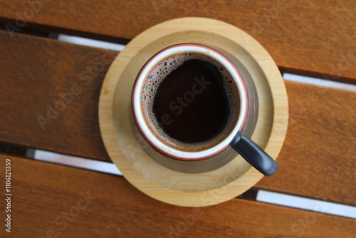 Cup of coffee on wooden table, top view