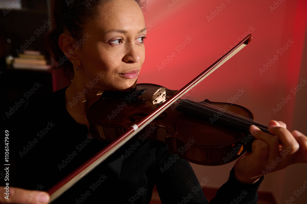 Focused woman playing violin in dramatic lighting Focused woman playing violin in dramatic lighting