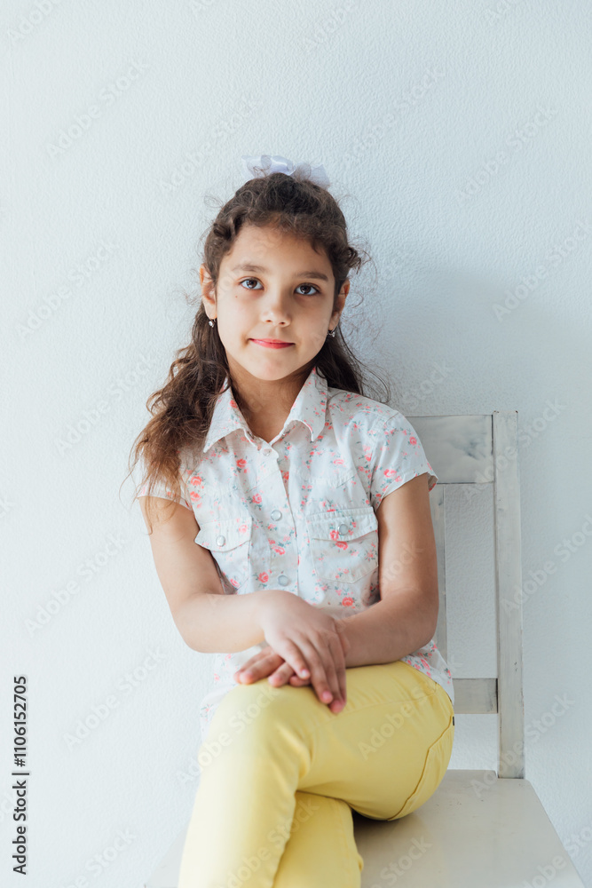 Little curly girl sitting on a white chair Little curly girl sitting on a white chair