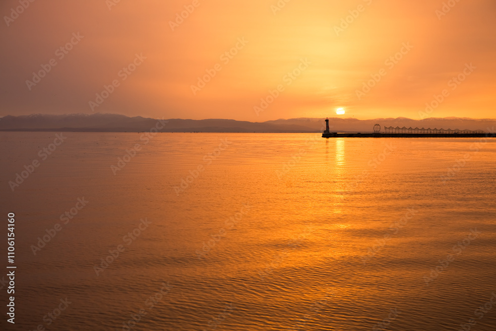 Fototapeta premium Sunset Over Calm Water with Pier in Distance 