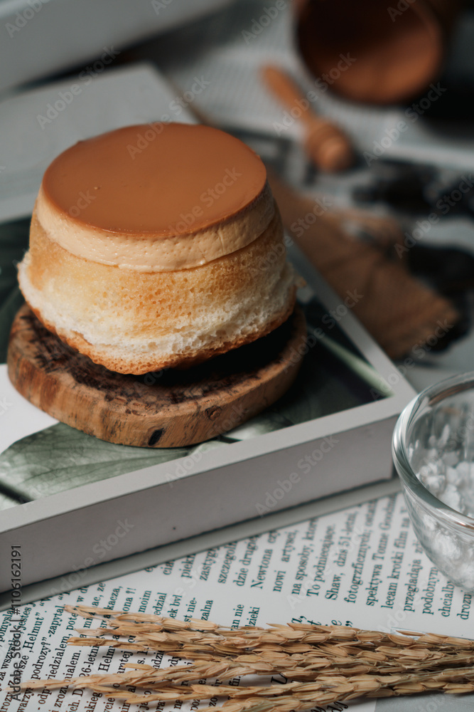 A delicate, round cake with a glossy brown top, resting on a wooden plate. A delicate, round cake with a glossy brown top, resting on a wooden plate.