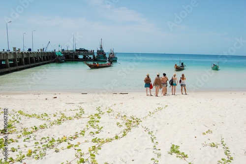 Group of five women about to board a boat, enjoying a serene tropical beach view in Thailand, looking at the ocean during a peaceful vacation, relaxing in a beautiful seaside landscape photo