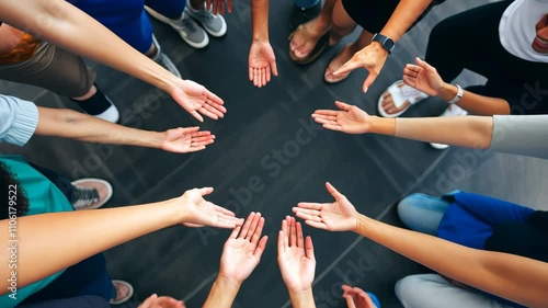 A group of people with different skin tones join their hands together in a circle, symbolizing unity, cooperation, and support