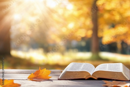 Autumn leaves surround an open book on a wooden table in a sunlit park