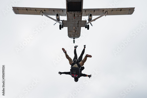Tandem skydive pair exit skyvan airplane under clouds