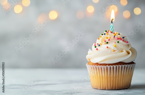 Colorful cupcake with candle and sprinkles on a background of soft lights