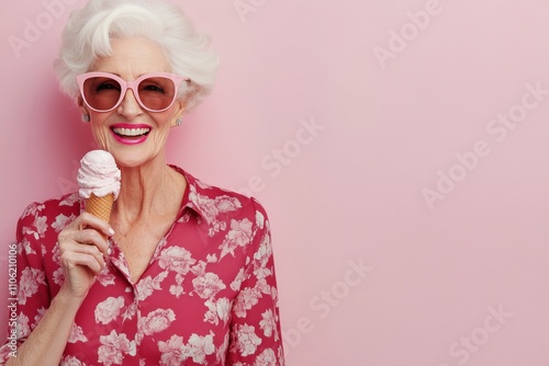 Joyful elderly woman enjoying ice cream against a pink background