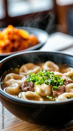 Delicious bowl of beef and dumpling soup with green onions and side of spicy ...