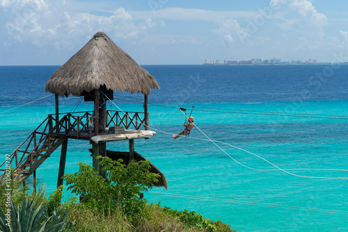 Vacation day on a tropical island in mexico with people on the zipline over the sea, extreme activities in Isla Mujeres