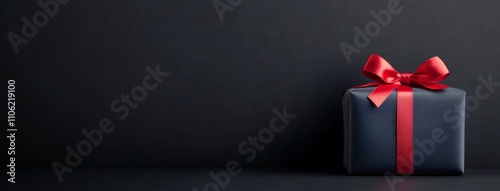 Gift box with red ribbon placed on dark background for special occasions or c...