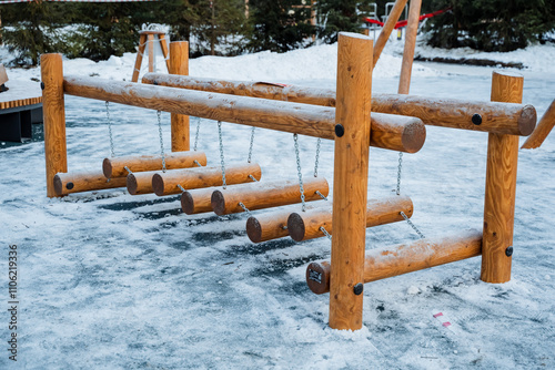 In the snowy park, a wooden obstacle course enhances the area with rustic elements like a splitrail fence and outdoor furniture, inviting visitors to enjoy the serene landscape photo