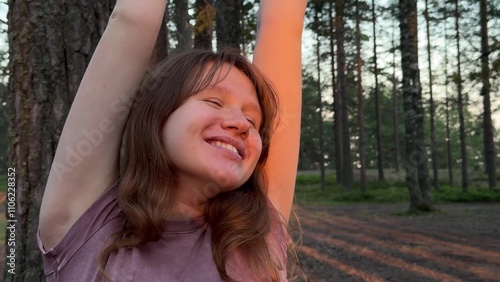 beautiful young woman enjoying golden sunset in pine forest