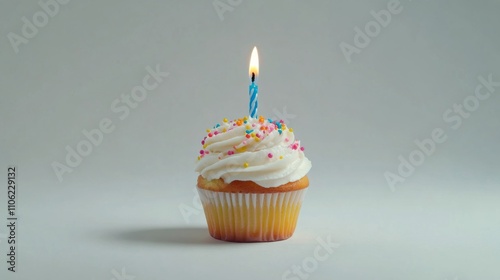Colorful cupcake with a lit candle on a plain background ready for celebration