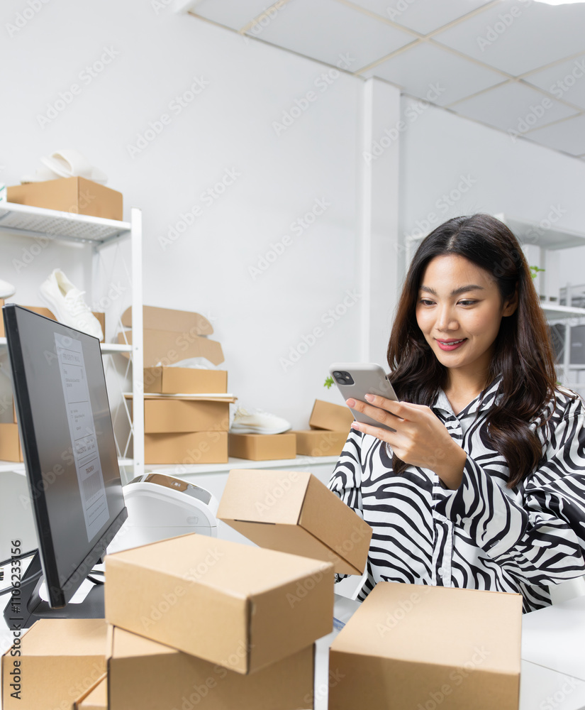 Asian female warehouse worker, small business owner preparing product to ship managing order using smartphone app scanning QR code to checking shipment detail for delivery at retail warehouse office. Asian female warehouse worker, small business owner preparing product to ship managing order using smartphone app scanning QR code to checking shipment detail for delivery at retail warehouse office.