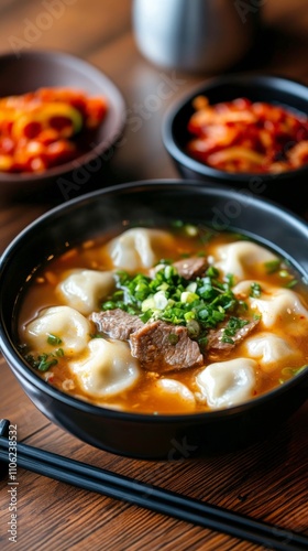 Delicious bowl of beef and dumpling soup with green onions and side of spicy ...