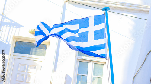 Bandeira da Grécia tremulando em uma viela de Mykonos, Grécia, com suas típicas casas brancas e ruas estreitas, capturando a essência da cultura e arquitetura grega photo