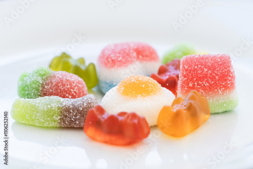 studio shot of a pile of multicolored jelly beans and sweets of various shapes and sizes on a clean white background. Concept of sweet colorful world, diabetes and excess sugar