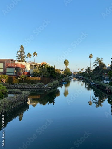 palm trees and houses are reflected in the water of the canal