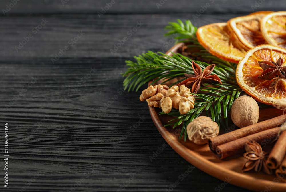 Different spices, dried orange slices and fir tree branches on black wooden table, closeup with space for text. Christmas season Different spices, dried orange slices and fir tree branches on black wooden table, closeup with space for text. Christmas season
