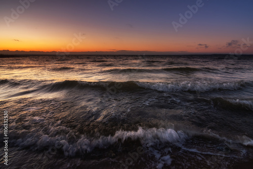 waves with breakers in stormy weather in a large raging lake in the warm light of the evening dawn. picturesque surf close-up, side view from below