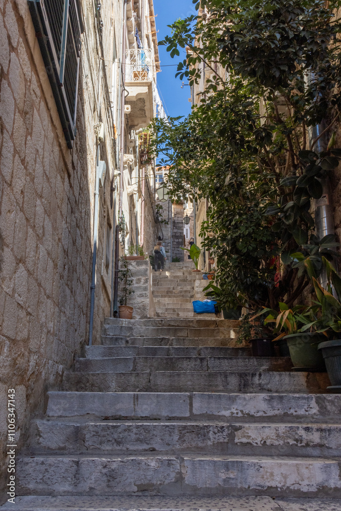 Obraz premium Dubrovnik, narrow street with wooden shutters, flowery balconies and warm lights. Steep stairs leading to small squares or churches. Croatia
