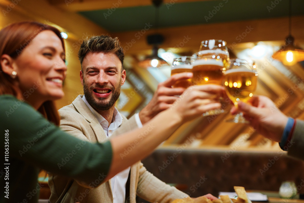 Happy friends are toasting with beer glasses enjoying a cheerful moment together in a restaurant Happy friends are toasting with beer glasses enjoying a cheerful moment together in a restaurant
