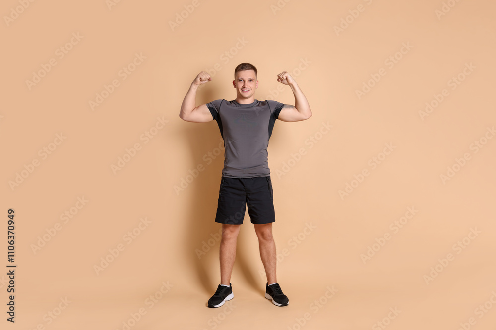 Happy winner showing his biceps on beige background Happy winner showing his biceps on beige background