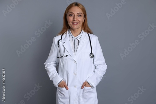 Smiling doctor with stethoscope on gray background