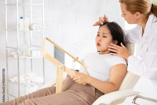 Asian woman listening to professional medicine worker about facial beauty procedure photo