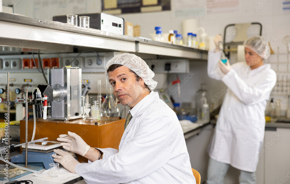 Obraz premium Professional middle-aged male scientist placing substance on stand for examination under microscope in research center