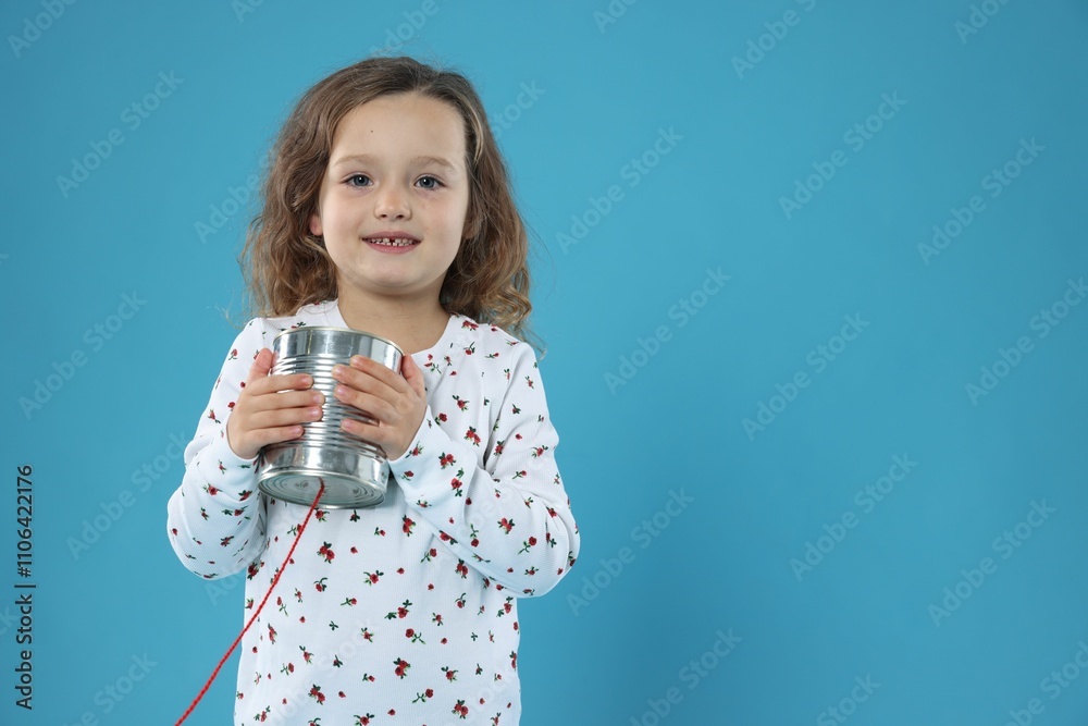 Girl using tin can telephone on blue background. Space for text Girl using tin can telephone on blue background. Space for text