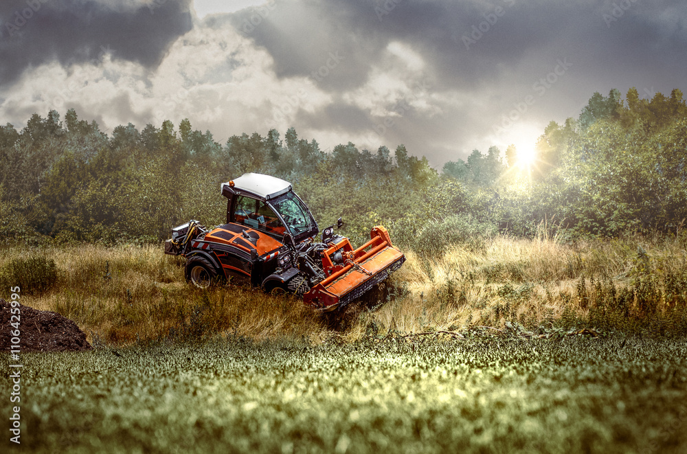 Fototapeta premium traktor mit rasenmäher schneidet hohes gras an einem hügel mit grünen gras im vordergrund und strahlendem sonnenschein
