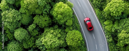 Red car driving on a curved road surrounded by dense green forest. Aerial view of a vehicle amidst nature