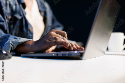 Close-up of hands of African American individual using laptop keyboard to type, browse the internet, work from home, and engage in freelance work. Black person working on personal computer. photo